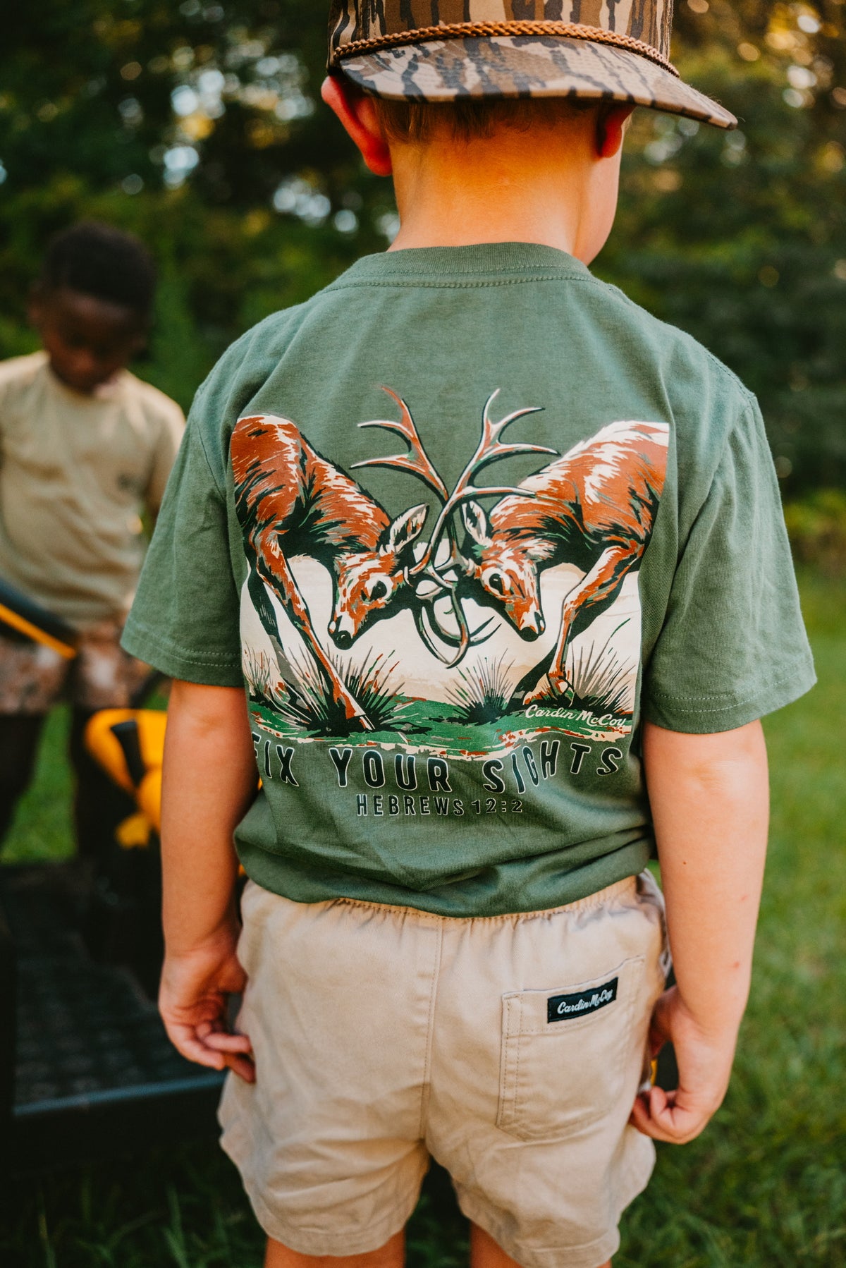 A child wearing a Fix Your Sights tee with Hebrews 12:2 on the back.
