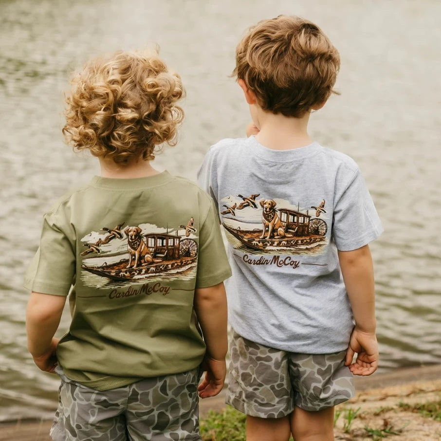 Two children wearing Cardin McCoy tees and camo shorts beside the water.