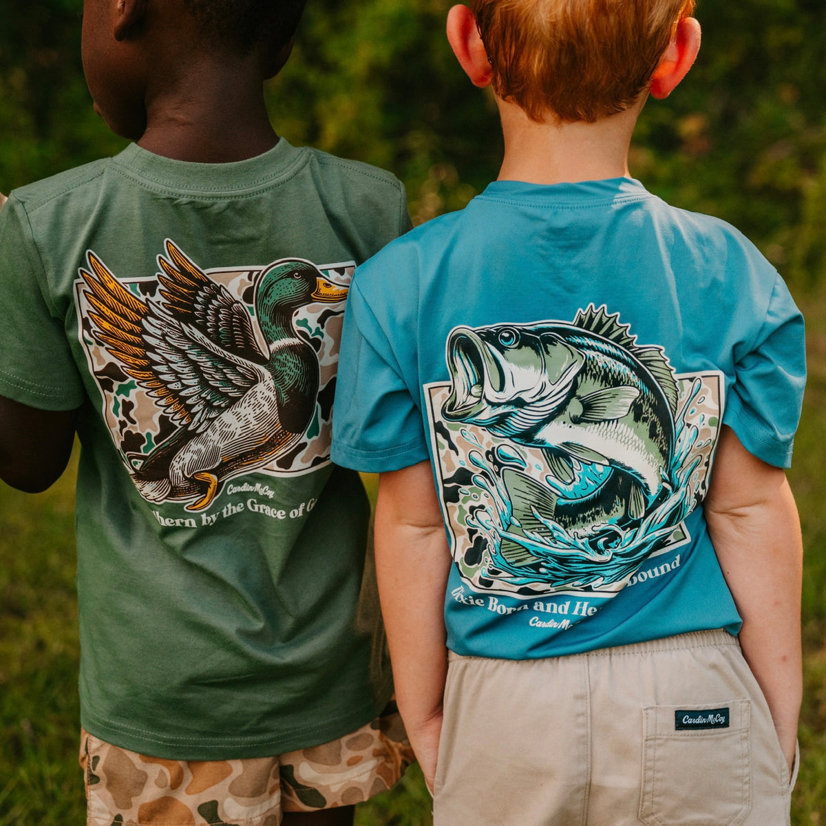 Child wearing a blue Cardin McCoy duck graphic tee beside a vehicle window in golden sunlight.