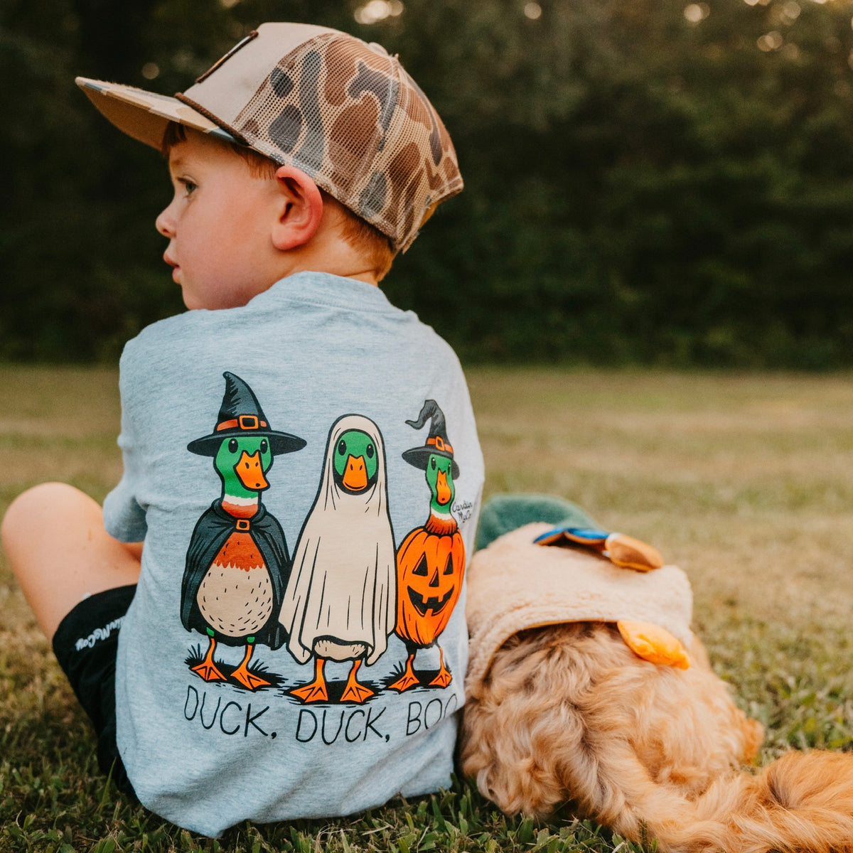 A child wearing a Cardin McCoy Duck, Duck, Boo tee beside a dog