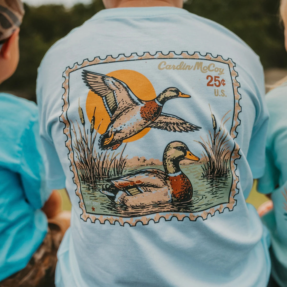 The Cardin McCoy duck stamp graphic on a light blue tee.