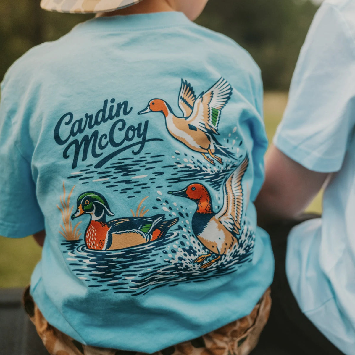 A child wearing a blue Cardin McCoy waterfowl graphic tee.